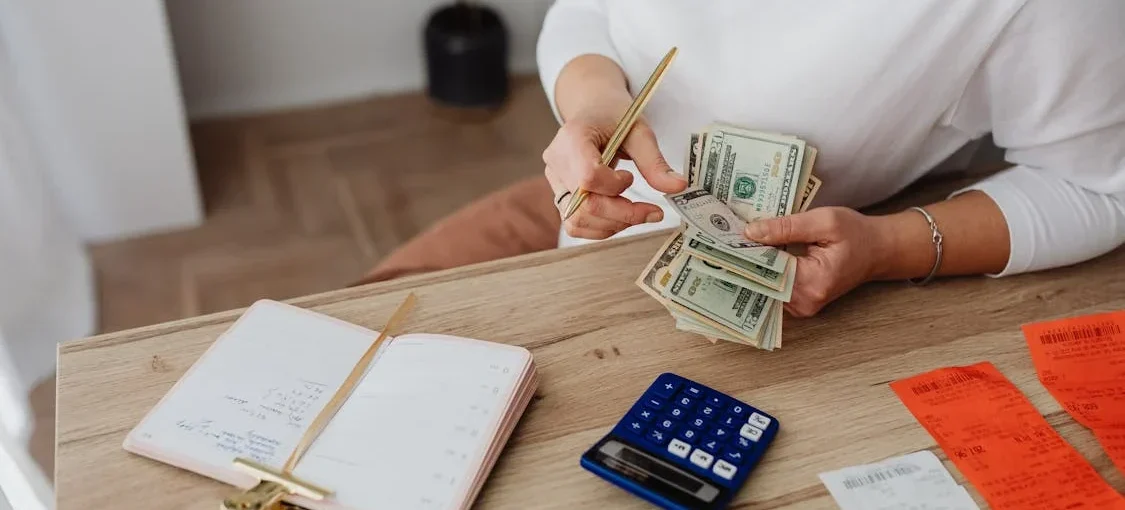 a woman counting money on a desk