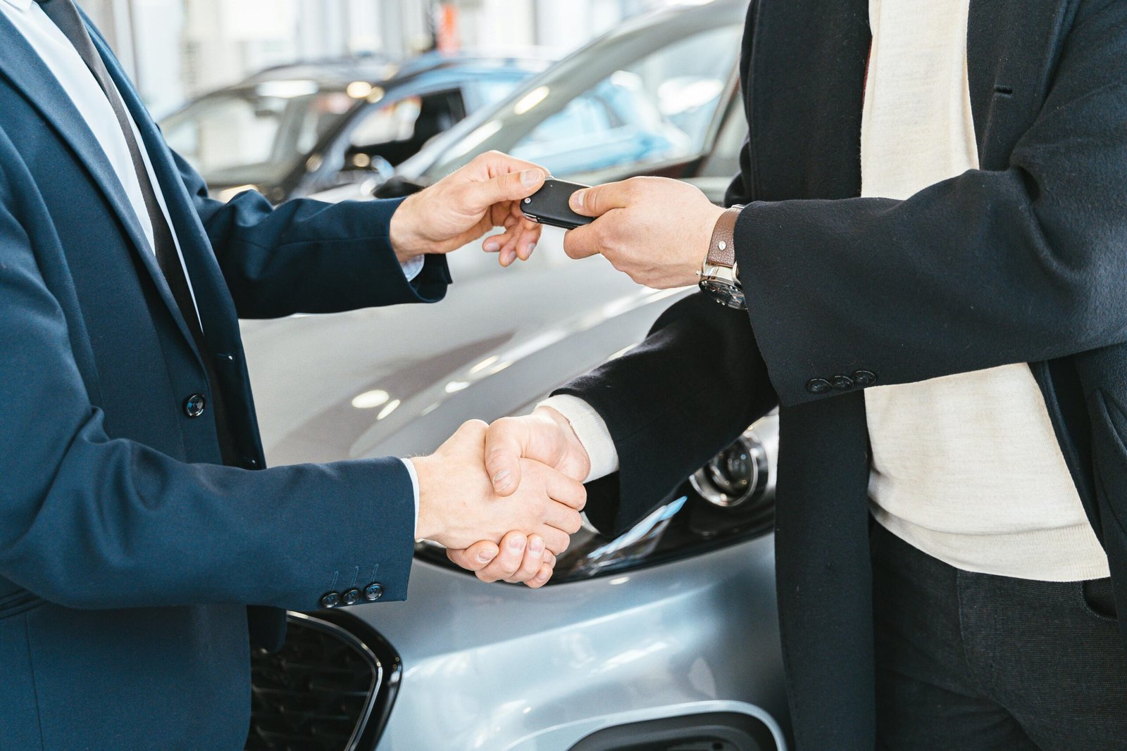 a car salesman handing over the keys to the new owner of the car