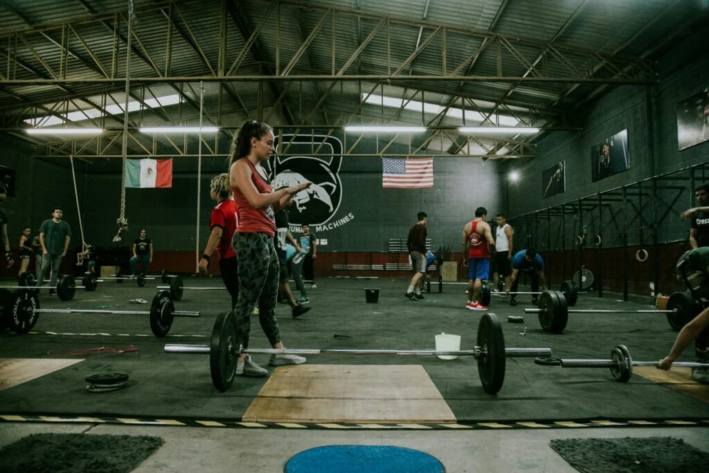 a busy gym at night highlighting a woman and a few gym goers at the background